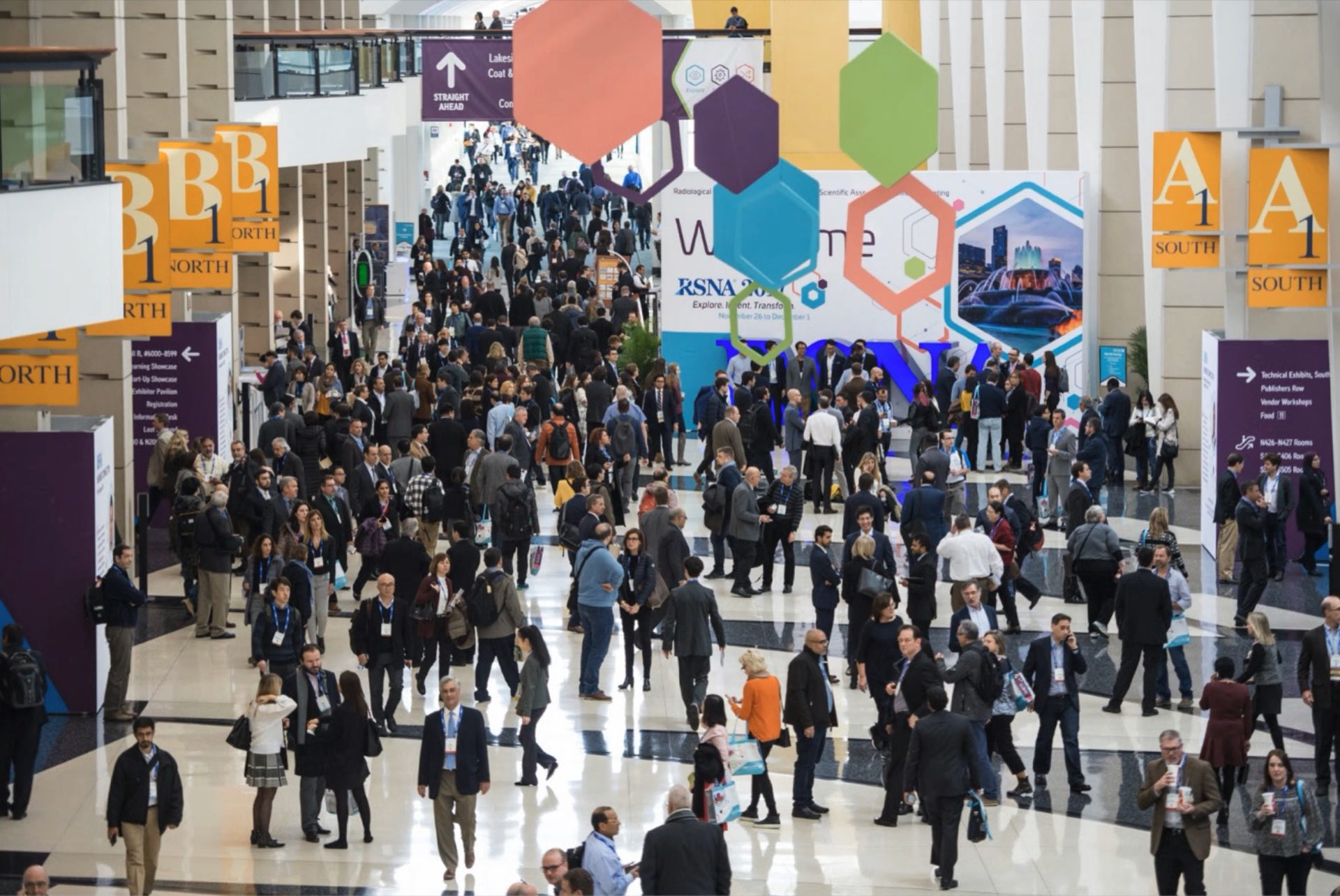 Delegates and their luggage moving through a convention centre concourse